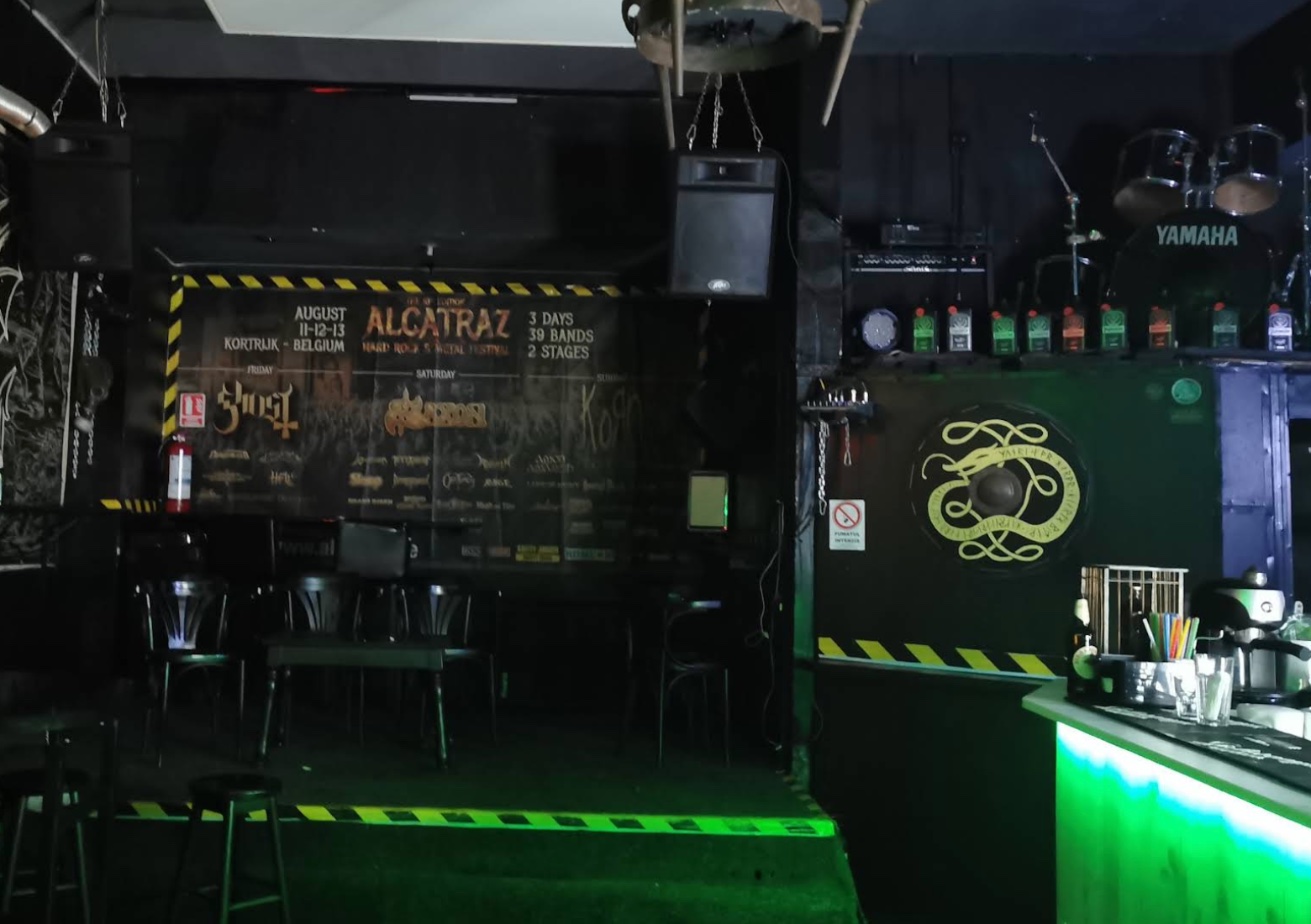Interiorul The Gate Bar: scena cu baterie, afișe de festival și barul luminat